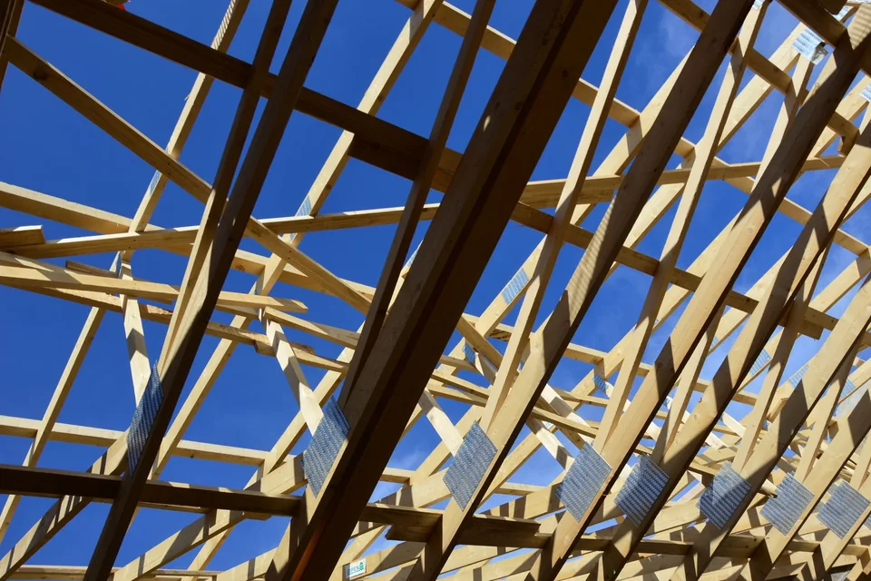 Fermettes de charpente en bois vues d'en dessous, ciel bleu