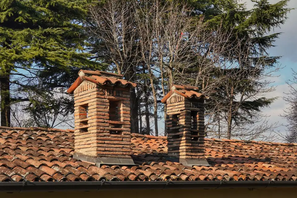 Deux souches de cheminée en brique sur un toit de tuiles
